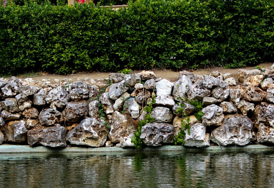 Limestone boulder retaining wall set by machine at a pond edge near Topeka